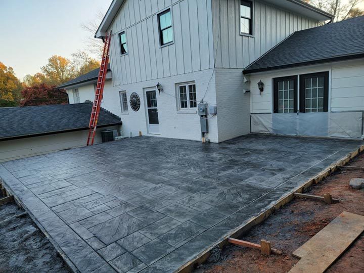 paver patio construction using concrete materials, a ladder leaning on the house exterior wall